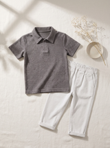 the truffle polo set laid flat: charcoal textured polo with collar, beside off-white salty white trousers with rolled cuffs